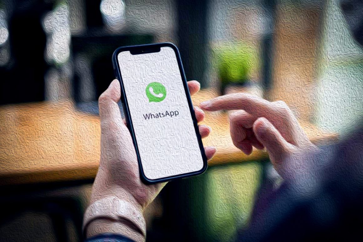 Uma pessoa segura um smartphone com o aplicativo WhatsApp aberto na tela