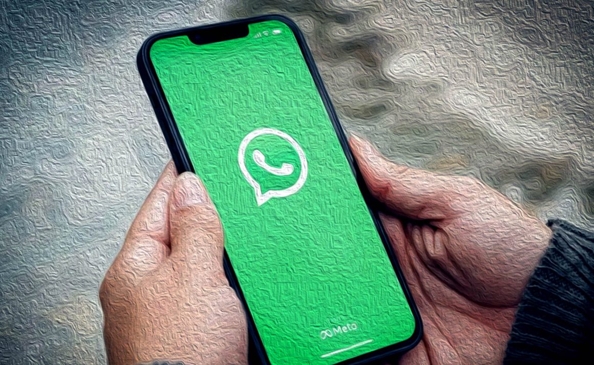 Mãos segurando telemóvel com a imagem inicial do WhatsApp